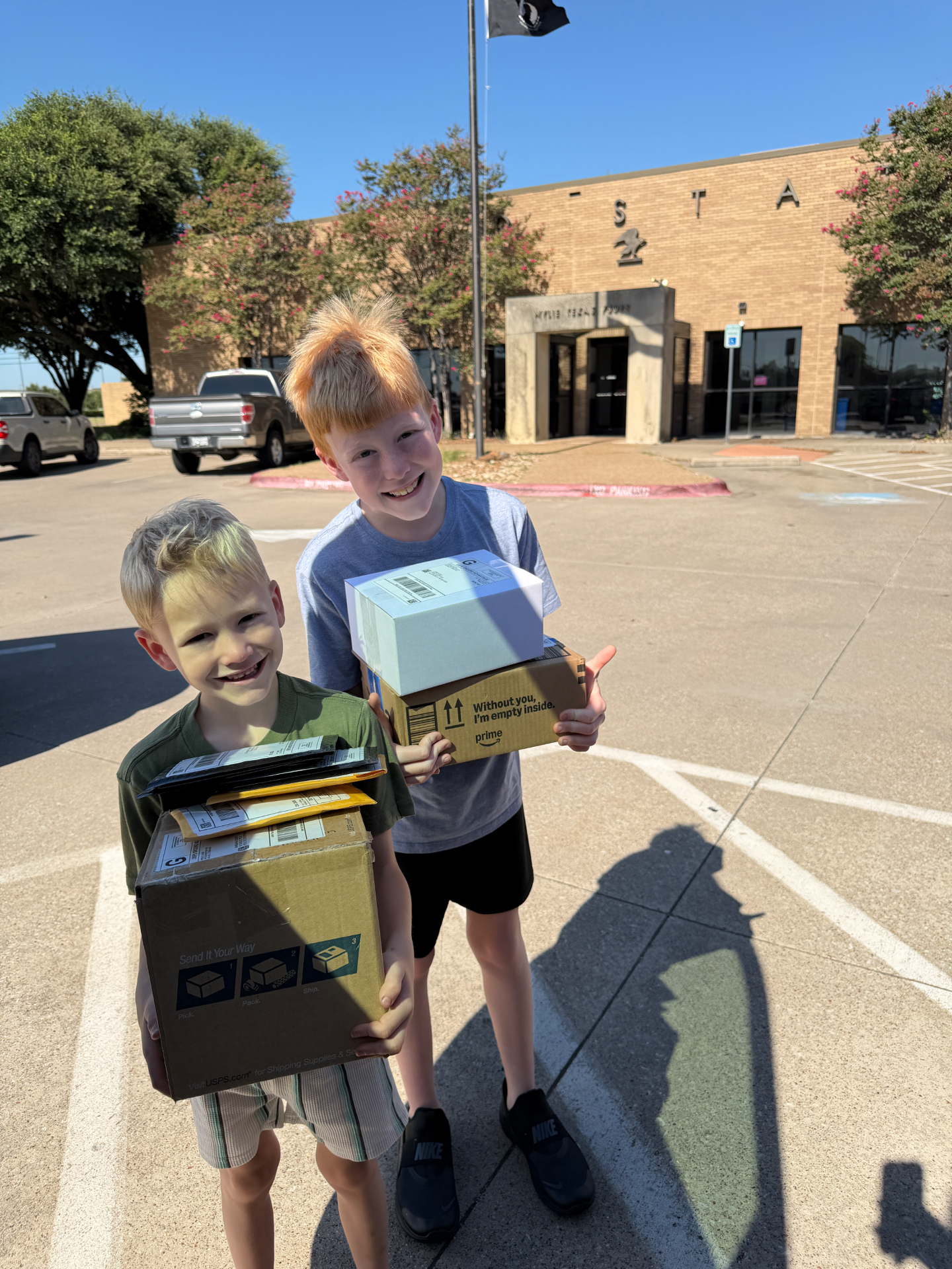 Our two sons smiling outside the post office, arms full of packages they're shipping